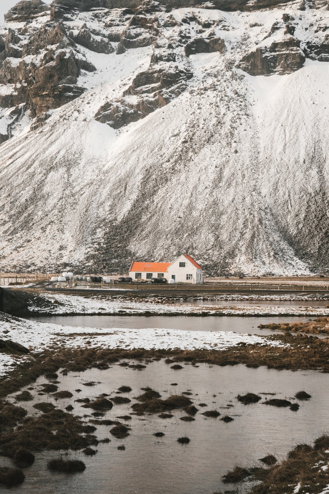 Lonely house near snowy mountain slope